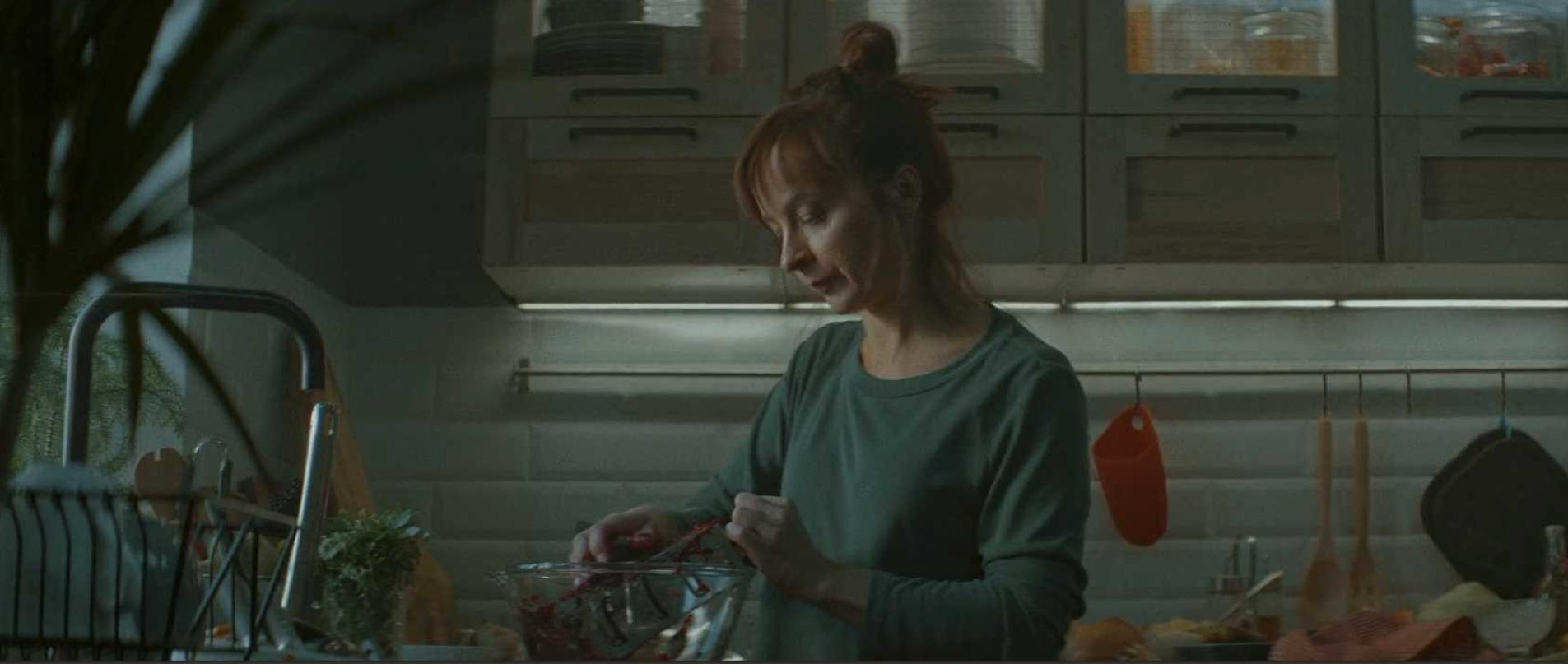 A woman making dinner in a dim kitchen at the end of the day.