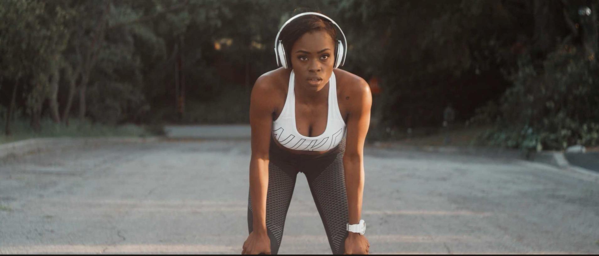 A runner stopped on the road, hands on her knees, catching her breath.