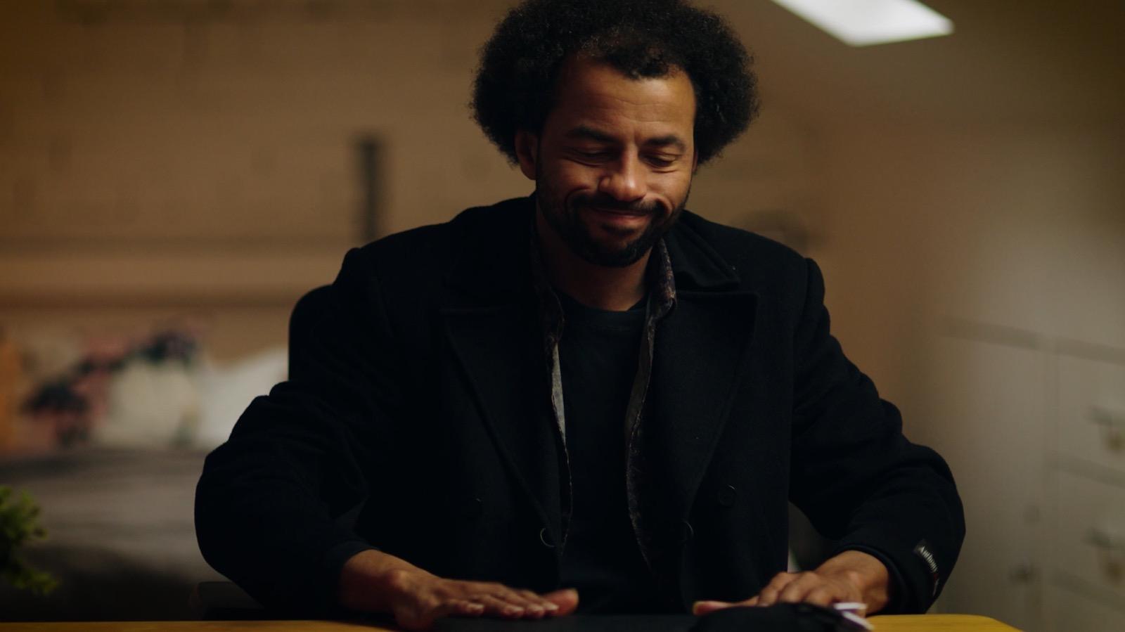 A man sitting at a kitchen table, looking away.